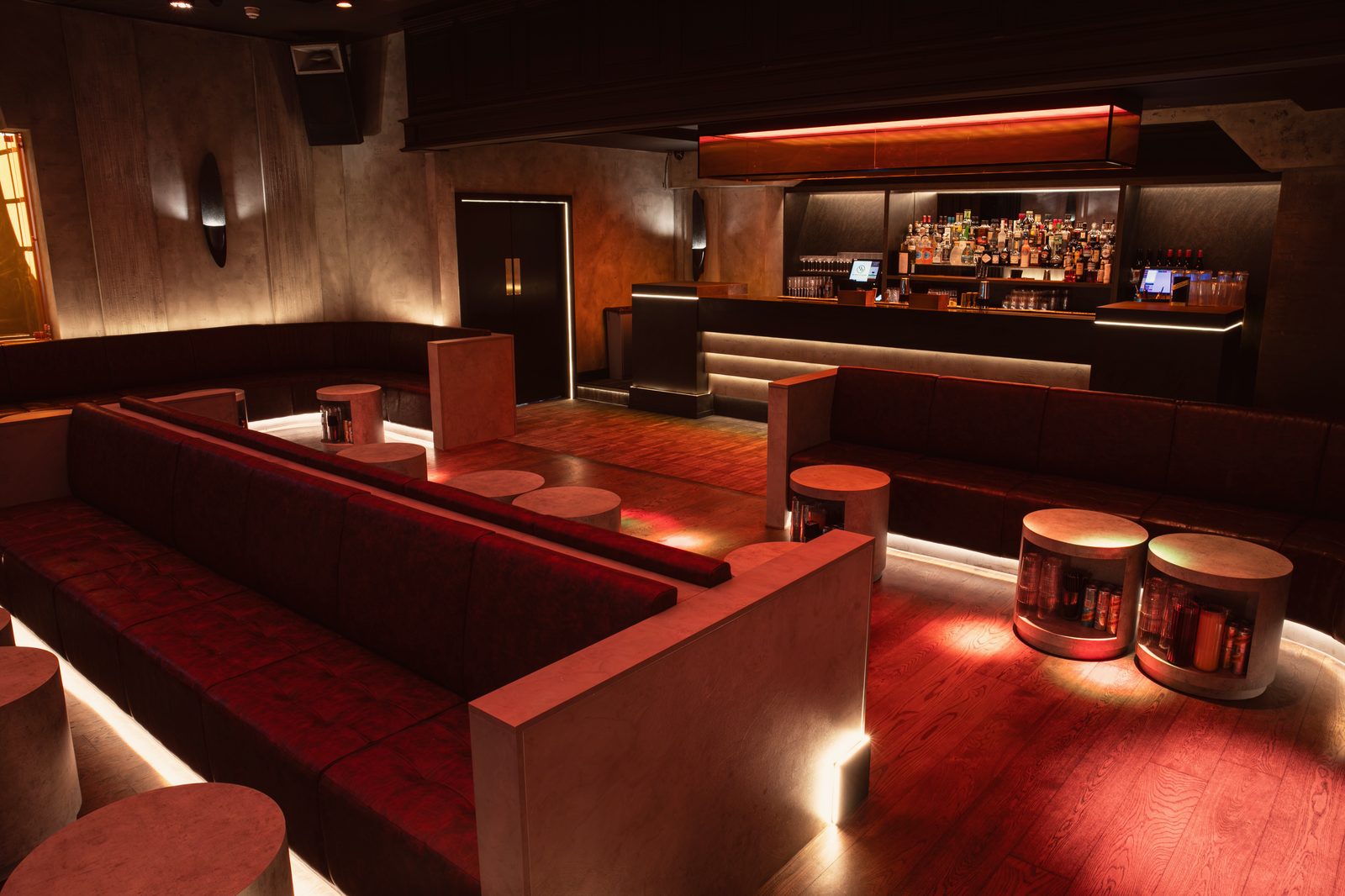 The Club Room: red leather banquettes and concrete drum tables, the bar beyond