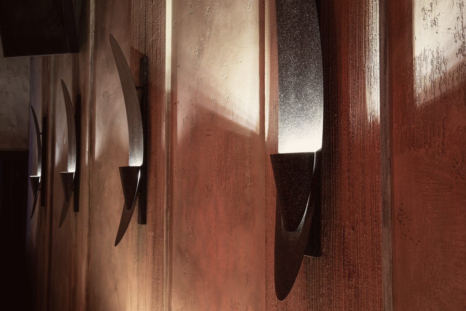 Dark metal wall lights throwing light up the plaster walls