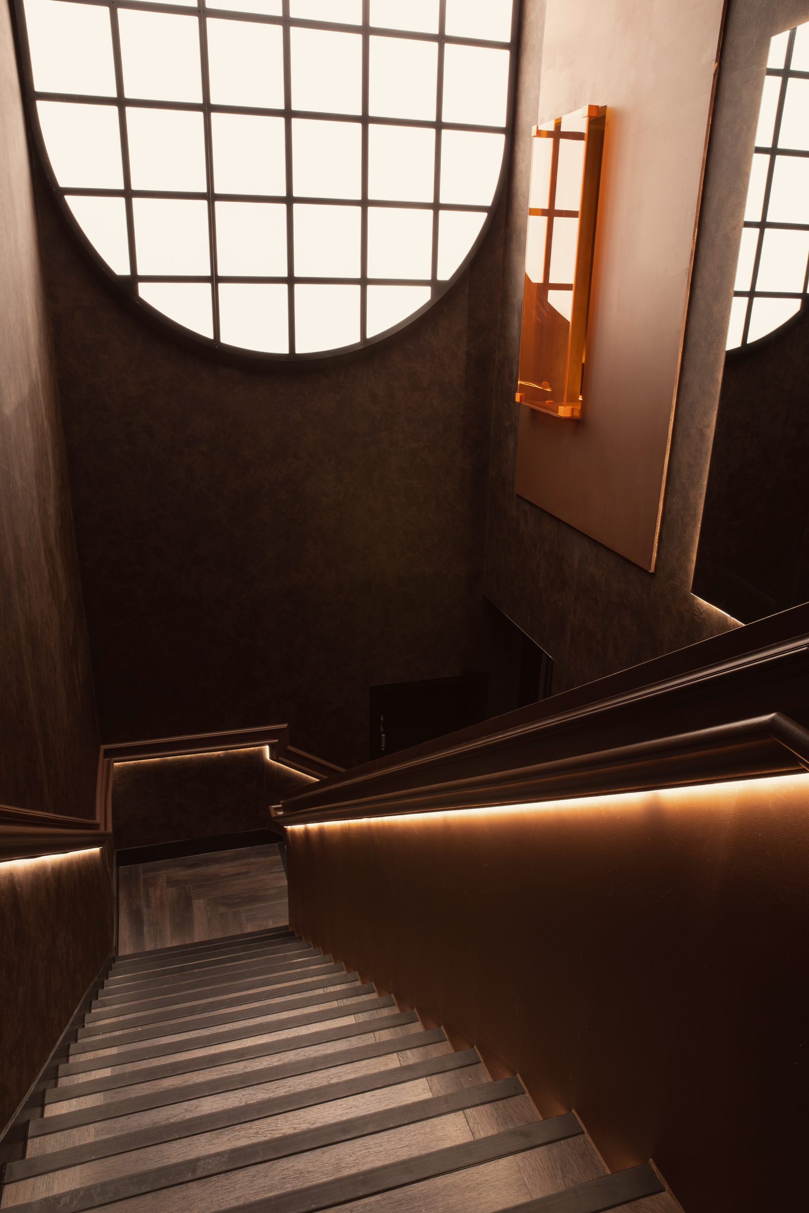 The staircase down into NinetyNine, its handrail lit from beneath