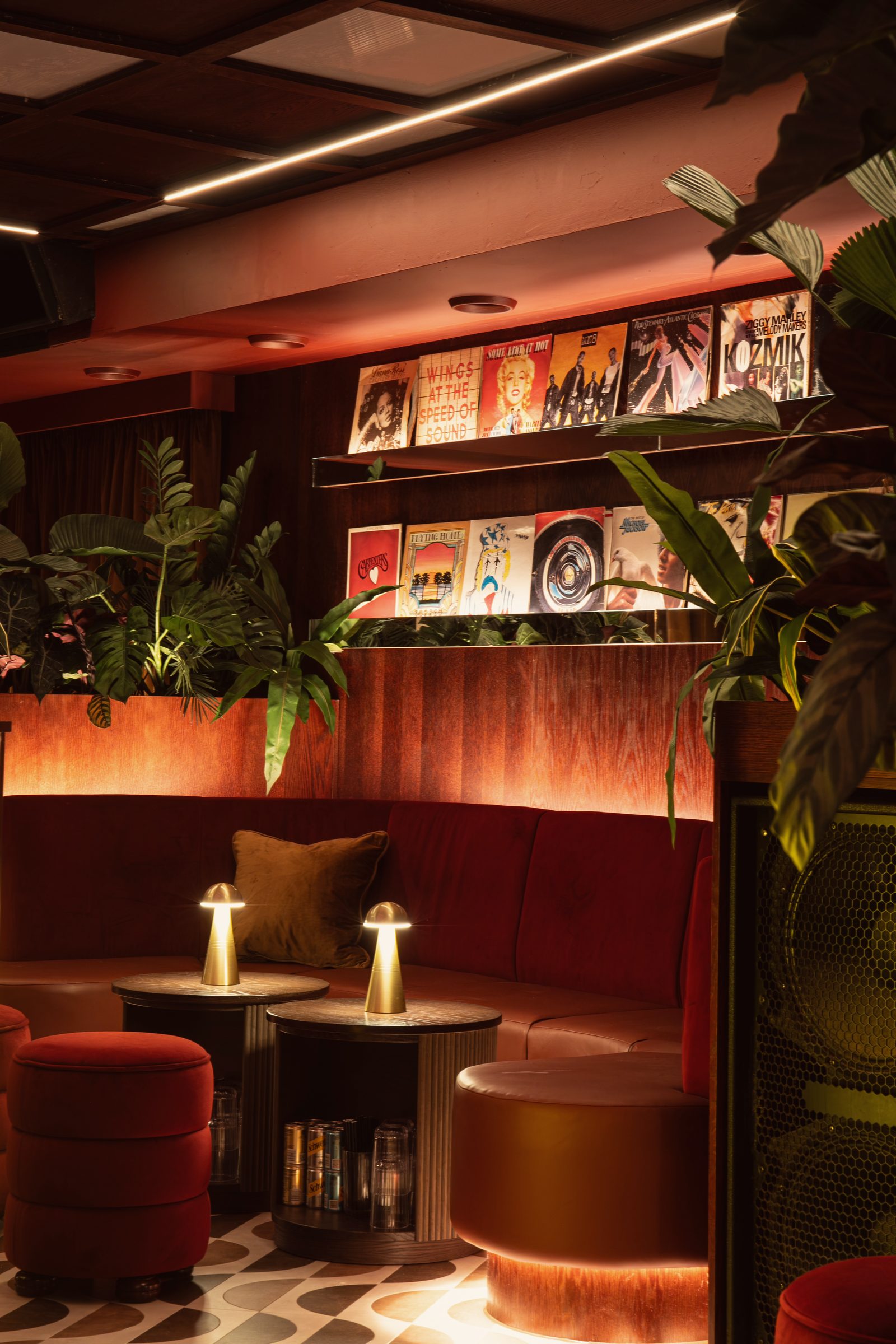 A Vinyl Room corner: red velvet banquette, bronze lamps and the record wall